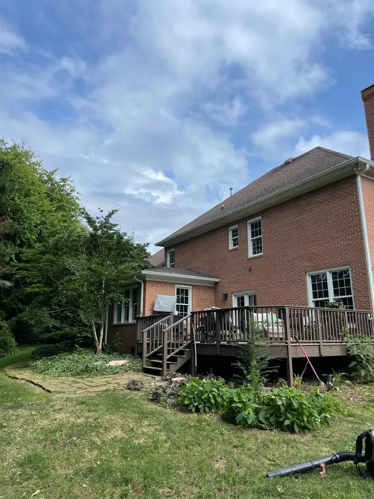 Cleared backyard behind a brick home with a deck, cleanup finished